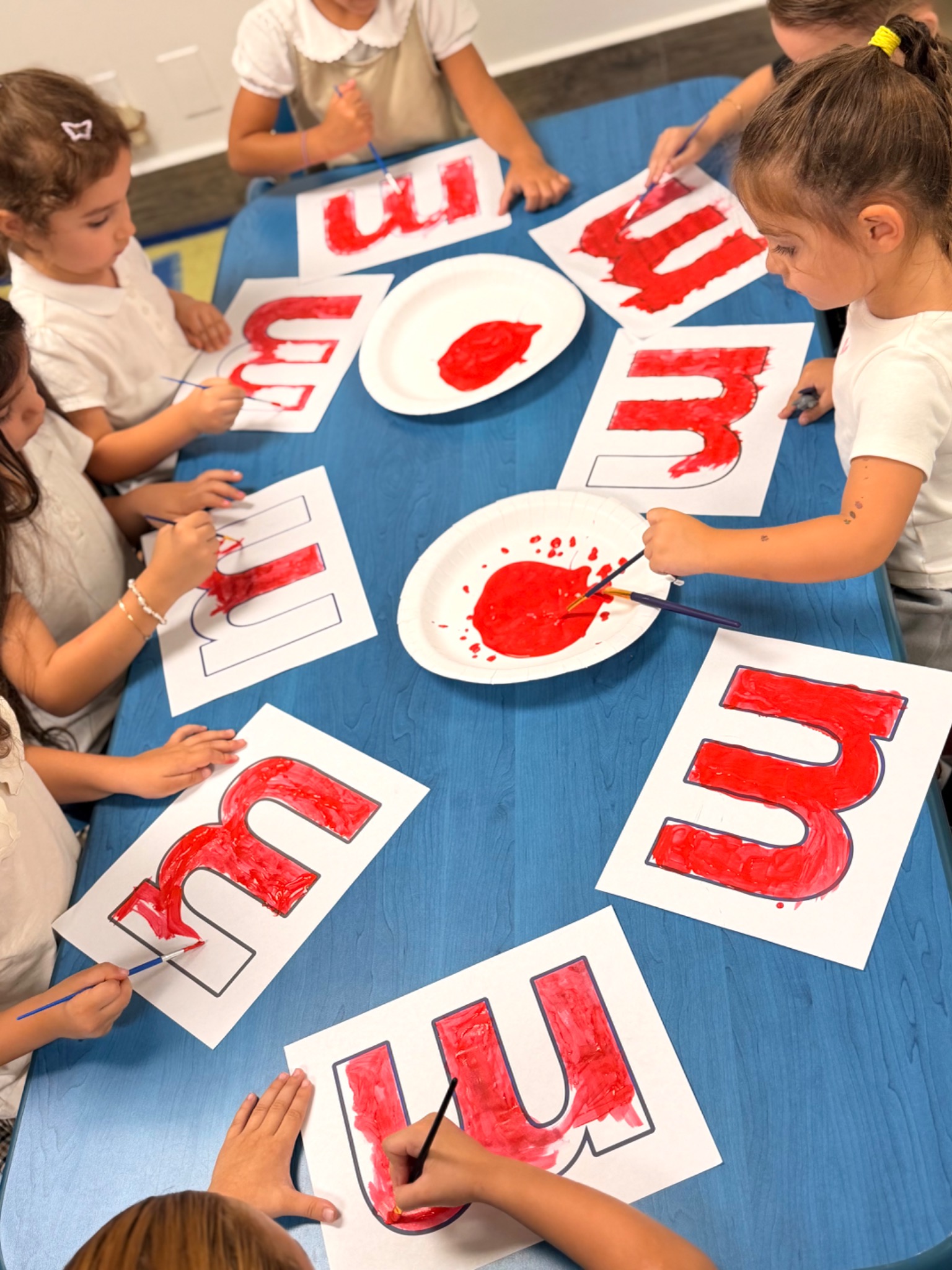 Kindergarten students painting Armenian letters during a hands-on literacy activity