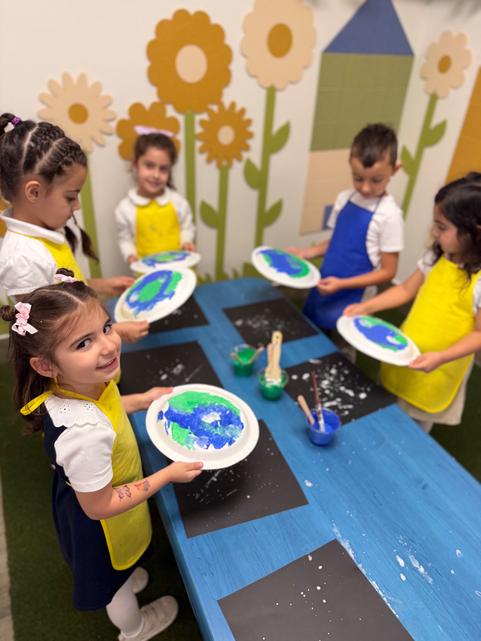 Kindergarten students creating Earth-themed artwork during a classroom project