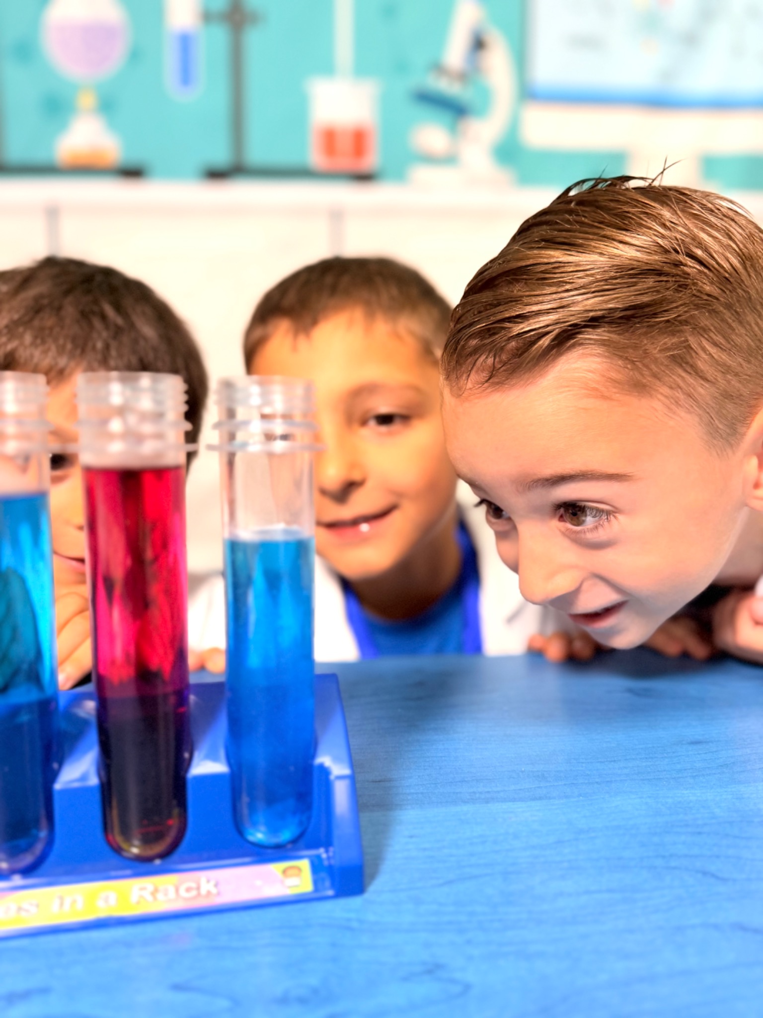 Kindergarten students observing colorful liquids in test tubes during a science activity