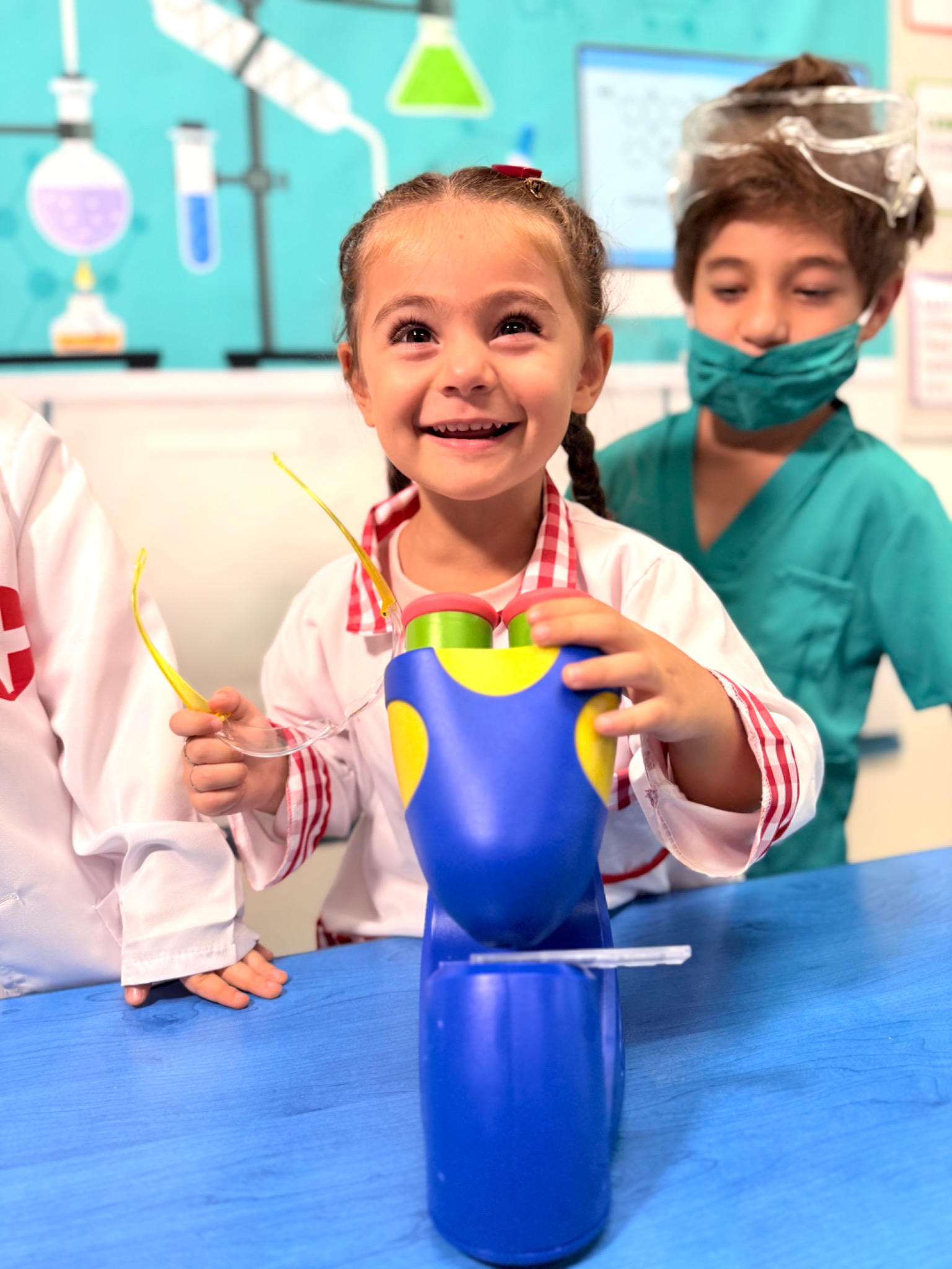 A kindergarten student pouring and mixing materials during a hands-on science experiment